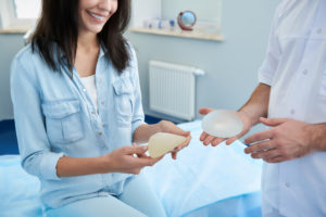 Woman at a plastic surgeon's office looking at different types of breast implants.