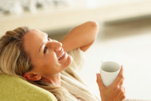 Smiling middle-aged woman with a cup of tea looking up