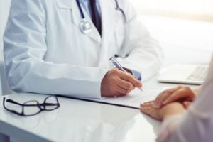 Doctor consults with his plastic surgery patient and writes notes on the clipboard.