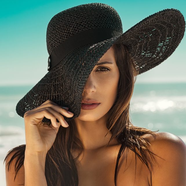 Woman at beach with big sun hat.