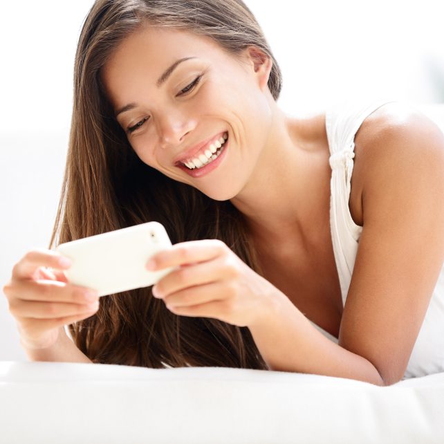 Woman laying on stomach reading a card.